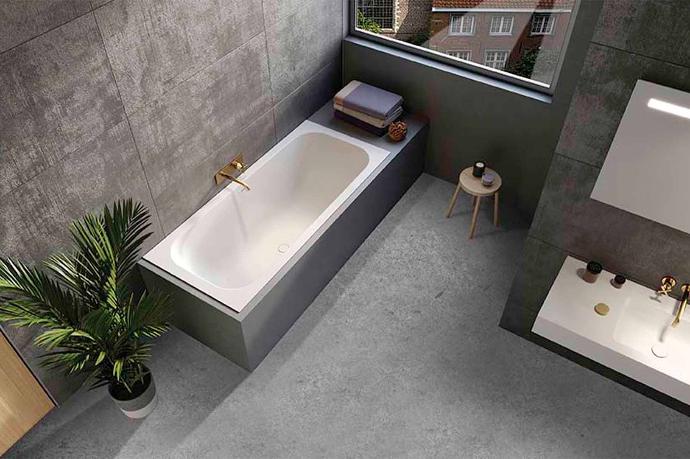 Strakke betonlook badkamer met wit hoekbad